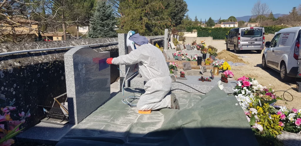 Artisan marbrier réalisant la gravure par sablage sur une stèle funéraire.
