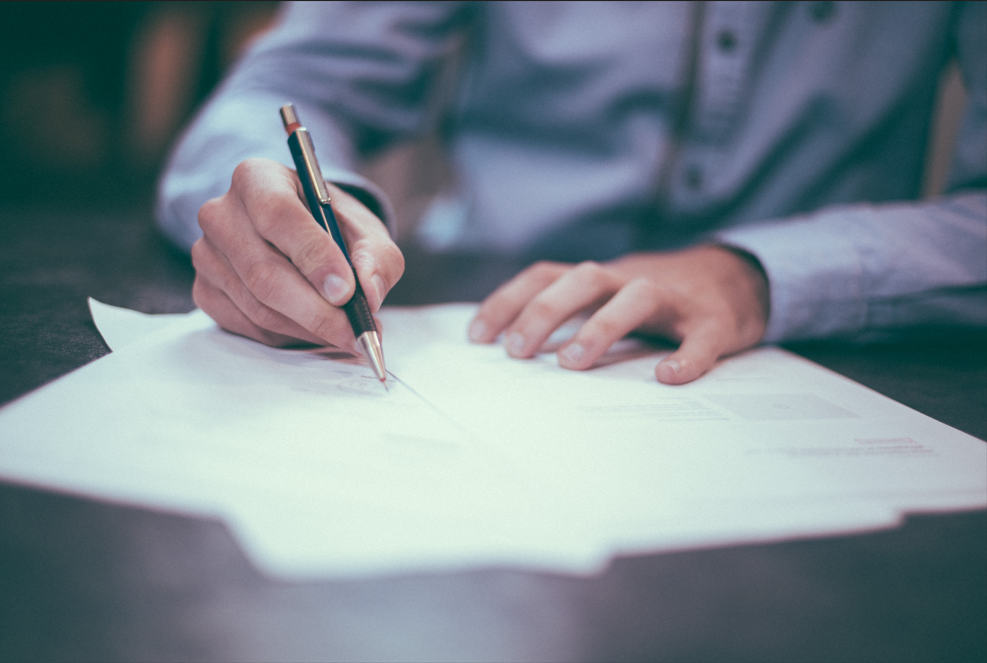 Homme signant des papiers administratifs, probablement pour l'organisation d'un décès.